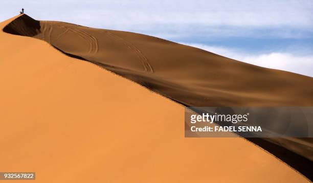 Man stands on a sand dune during the "Gallops of Morocco" equestrian race in the desert of Merzouga in the southern Moroccan Sahara desert on March...