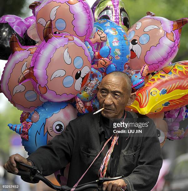 Man smokes as he peddles balloons along a street in Beijing on May 6, 2009. A Chinese county has dropped a plan to order its officials to...