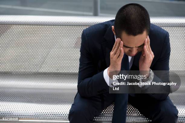 mixed race businessman sitting on bench with head in hands - head of the bank stock-fotos und bilder