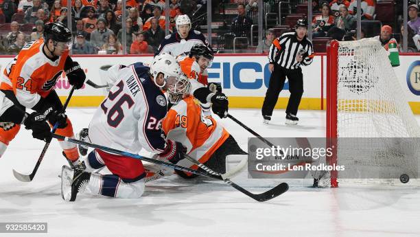 Goaltender Alex Lyon of the Philadelphia Flyers sprawls across his crease as Matt Read and Andrew MacDonald defend against Thomas Vanek of the...