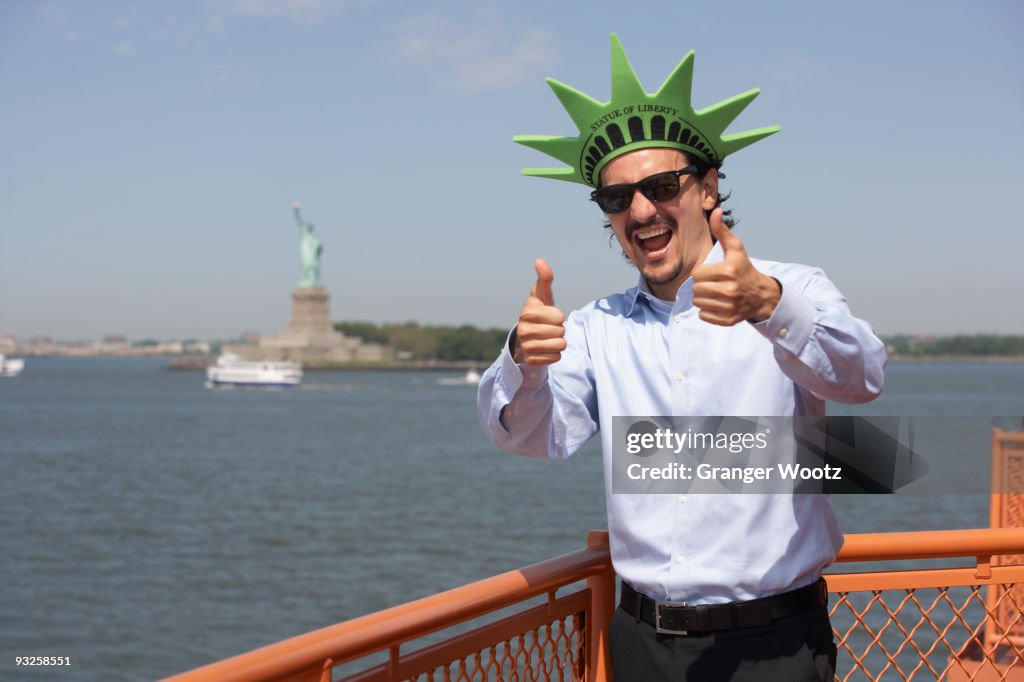 Mixed race businessman on ferry wearing Statue of Liberty hat