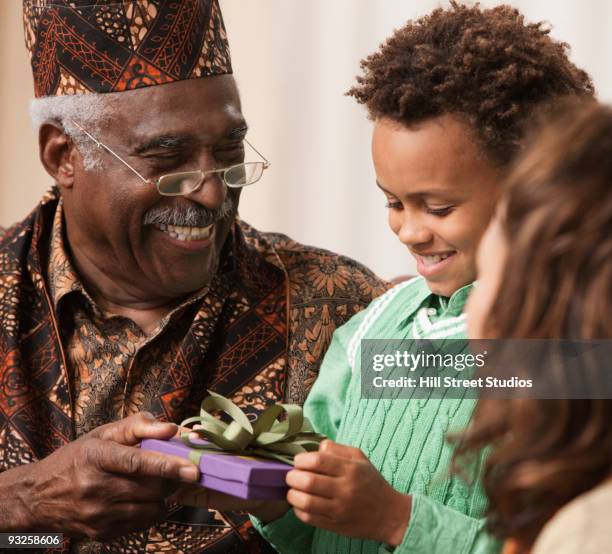 grandfather giving grandson kwanzaa gift - kwanzaa stock pictures, royalty-free photos & images