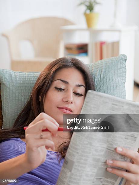 hispanic woman doing newspaper crossword puzzle - crossword stock pictures, royalty-free photos & images