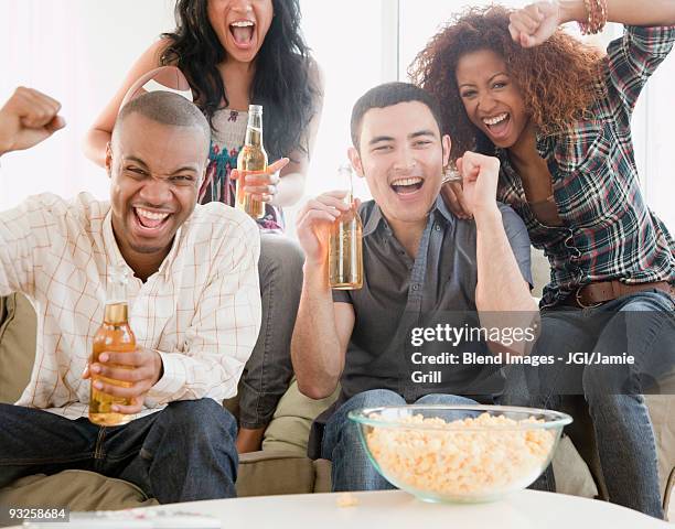 friends drinking beer and watching football on television - beer bottle mouth stock-fotos und bilder