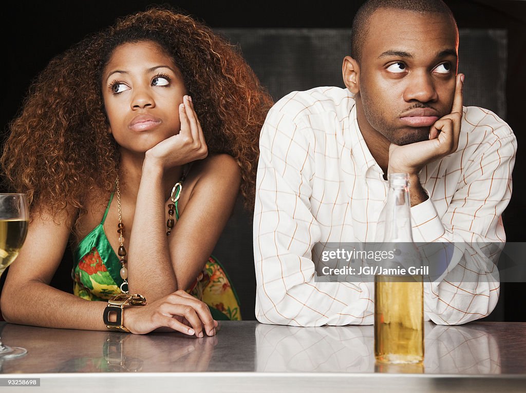 Couple sitting at bar and looking irritated