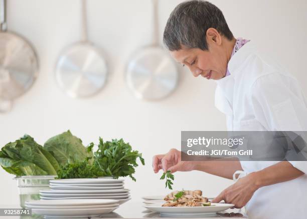 chinese chef plating meals in professional kitchen - food plating stock-fotos und bilder