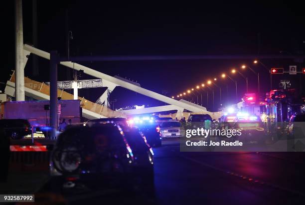 Lights illuminate the scene as Miami-Dade Fire Rescue Department personel and other rescue units work at the scene where a pedestrian bridge...