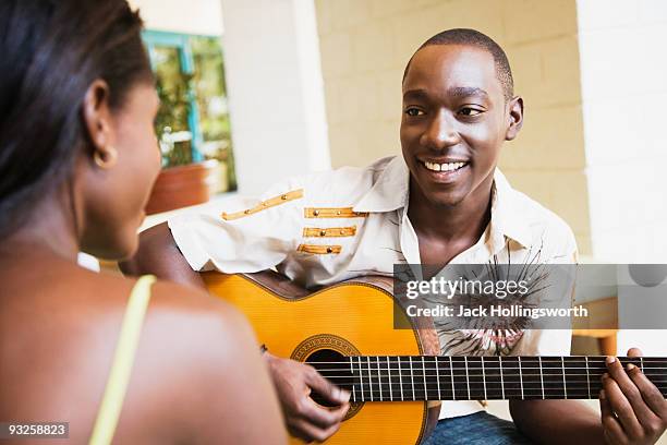 african man playing guitar for woman - cantare una serenata foto e immagini stock