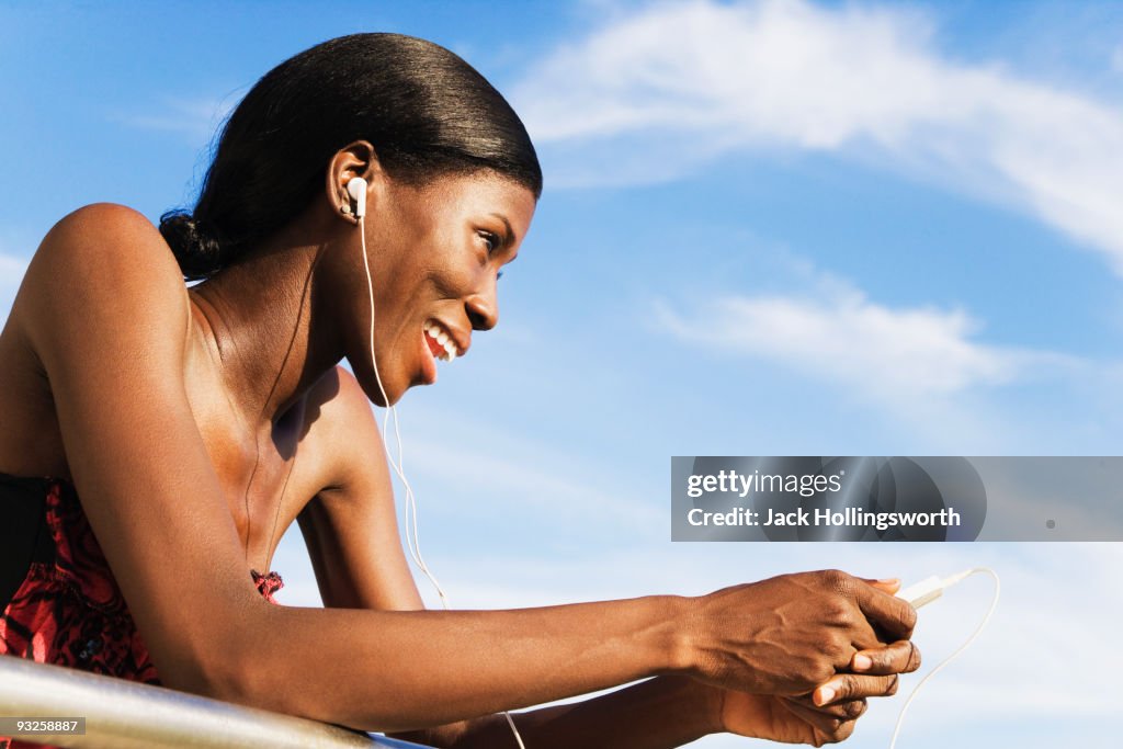 African woman wearing headphones and holding MP3 player