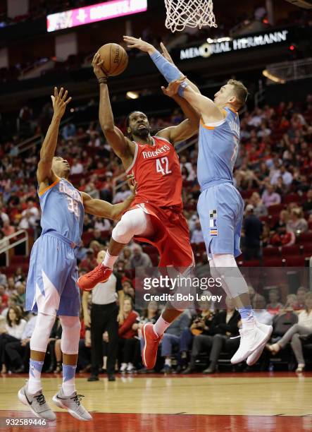 Nene of the Houston Rockets drives to the basket between Sam Dekker of the LA Clippers and Wesley Johnson at Toyota Center on March 15, 2018 in...