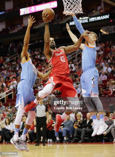 Nene of the Houston Rockets drives to the basket between Sam Dekker of the LA Clippers and Wesley Johnson at Toyota Center on March 15, 2018 in...