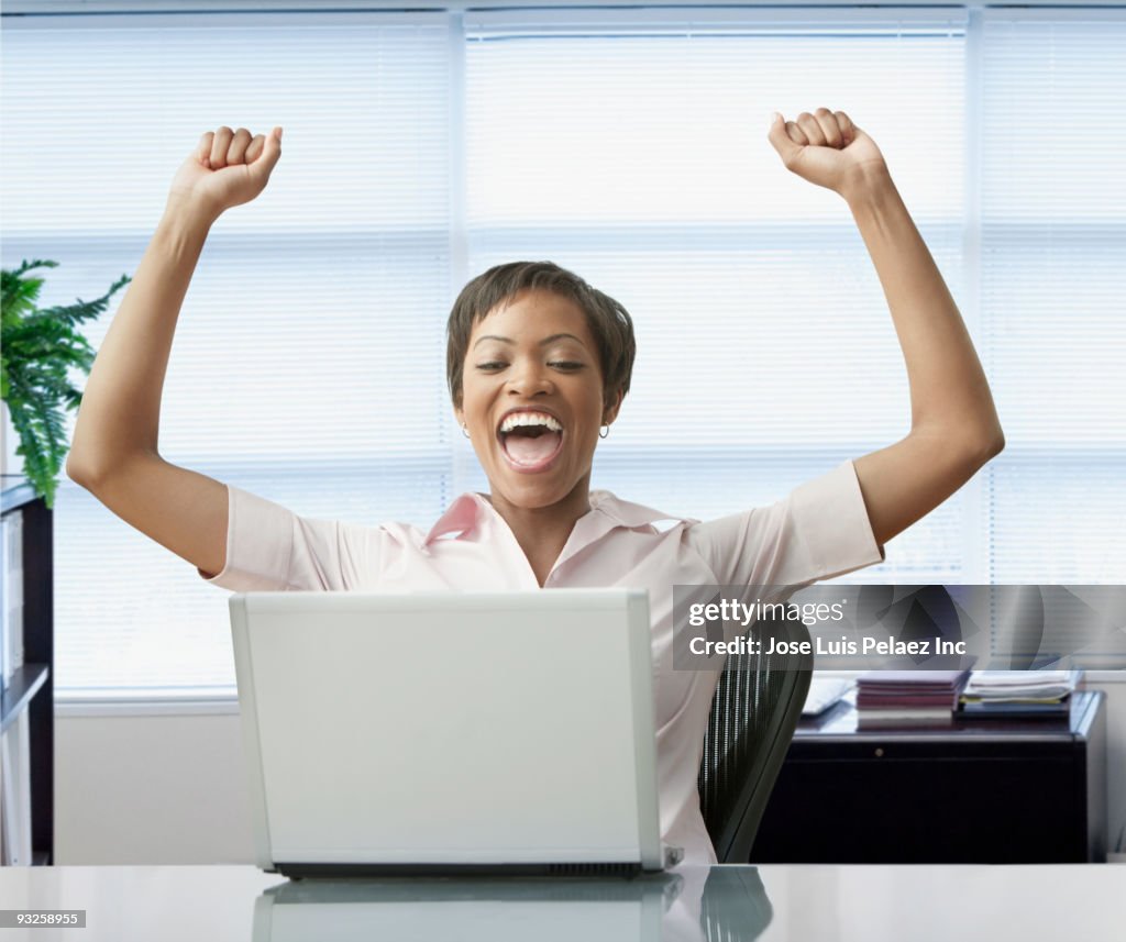 African woman with laptop celebrating