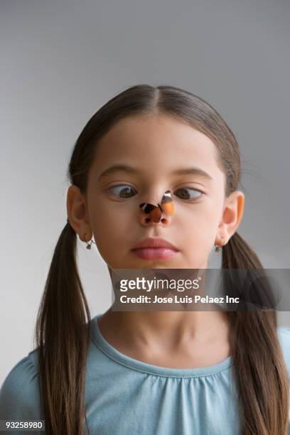 hispanic girl staring cross-eyed at butterfly on nose - human nose isolated stock pictures, royalty-free photos & images