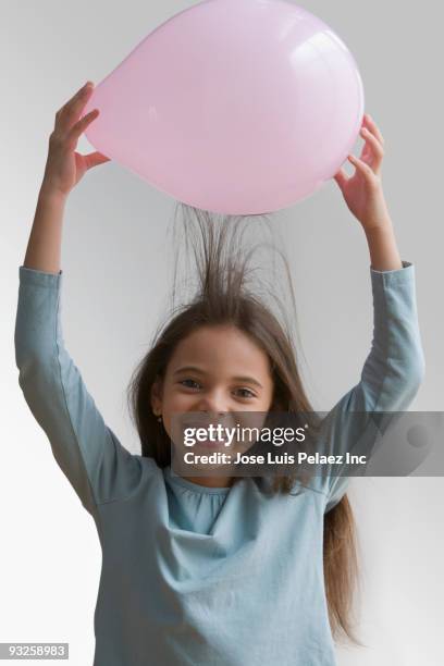 hispanic girl creating static in hair with balloon - child balloon studio photos et images de collection
