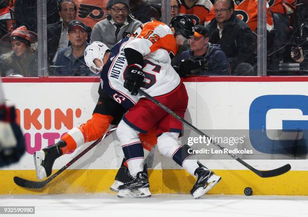 Markus Nutivaara of the Columbus Blue Jackets checks Michael Raffl of the Philadelphia Flyers into the boards as they battle for the loose puck on...