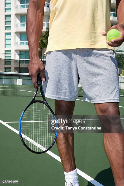 african man holding tennis ball and racket - schlägersport stock-fotos und bilder