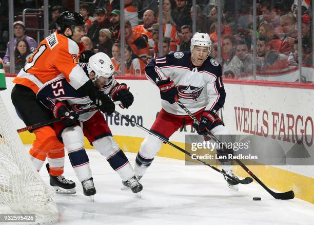 Matt Calvert of the Columbus Blue Jackets controls the puck along the boards behind the net as Mark Letestu defends against Scott Laughton of the...