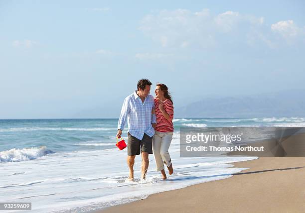 couple walking on beach together  - ankle deep in water stock pictures, royalty-free photos & images