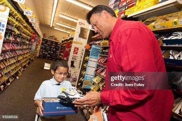 Anthony Munoz helps a young kid pick out a pair of shoes at Payless ShoeSource on November 20, 2009 in Cincinnati, Ohio.
