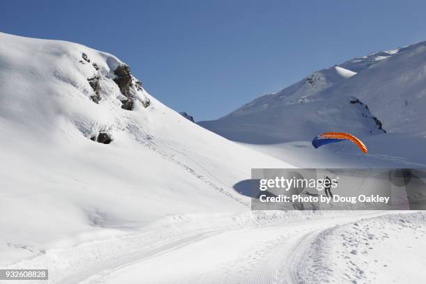 man on skis wearing a parachute in french alps - chute ski stock-fotos und bilder