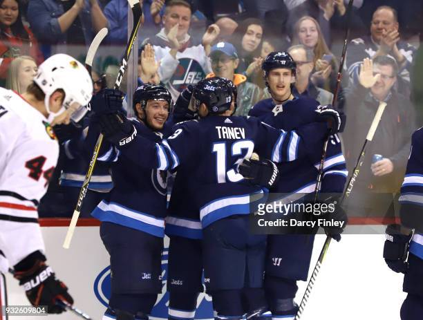 Marko Dano, Brandon Tanev and Tyler Myers of the Winnipeg Jets celebrate a first period goal against the Chicago Blackhawks at the Bell MTS Place on...