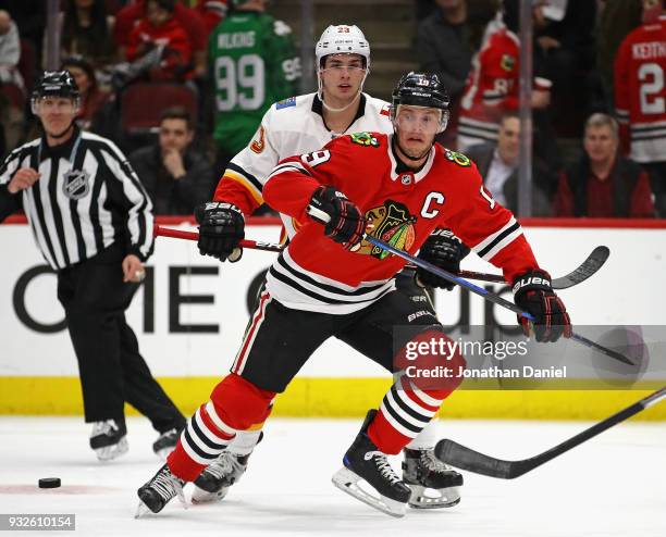 Jonathan Toews of the Chicago Blackhawks skates to the puck in front of Sean Monahan of the Calgary Flames at the United Center on February 6 2018 in...