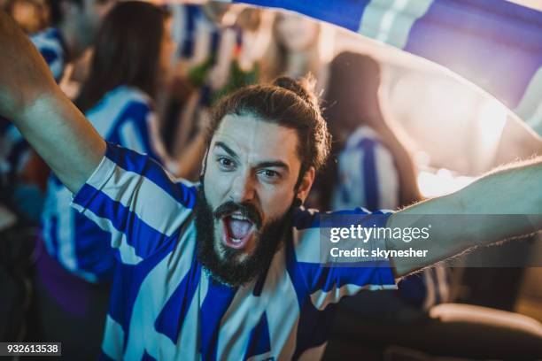 ung man skriker och hejar för hans favorit fotbollslag medan du tittar på en match på tv i vardagsrummet. - fan scarf bildbanksfoton och bilder