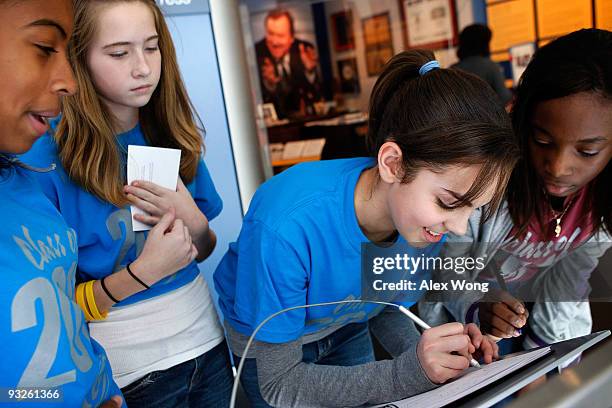 Seventh grader Daniella Ludwig of Harper Park Middle School in Leesburg, Virgiinia, signs the guestbook as fellow students Amina Johnson, Tessa...