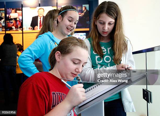 Seventh grader Sammi Ash of Dixon Smith Middle School in Stafford, Virginia, signs the guestbook as fellow students Tiffany Nicholson and Kelsey...