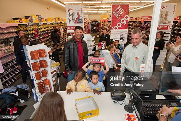 Anthony Munoz helps children lineup to give the cashier the coupons for their new shoes at Payless ShoeSource on November 20, 2009 in Cincinnati,...