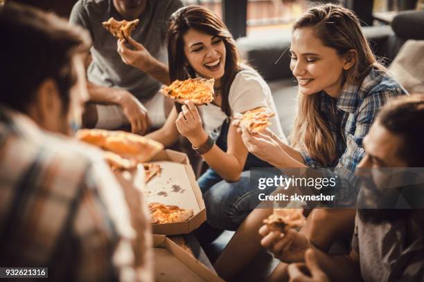 young happy friends having fun while eating pizza at home. - pizza stock pictures, royalty-free photos & images