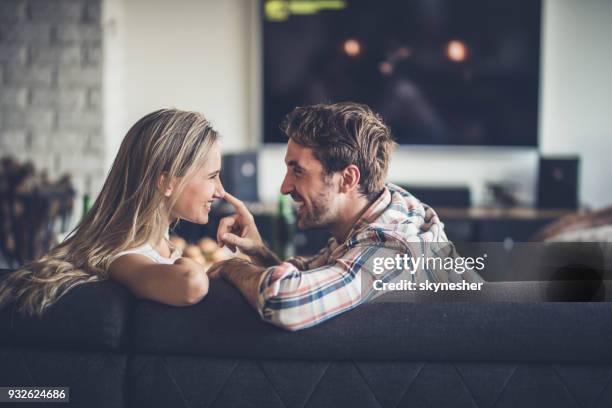 profiel te bekijken van gelukkige paar ontspannen op de sofa thuis en met elkaar praten. - romantische activiteit stockfoto's en -beelden