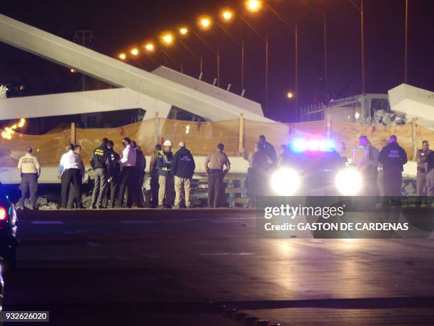 Police lights illuminate the scene of a pedestrian bridge collapse in Miami, Florida on March 15 crushing a number of cars below and reportedly...