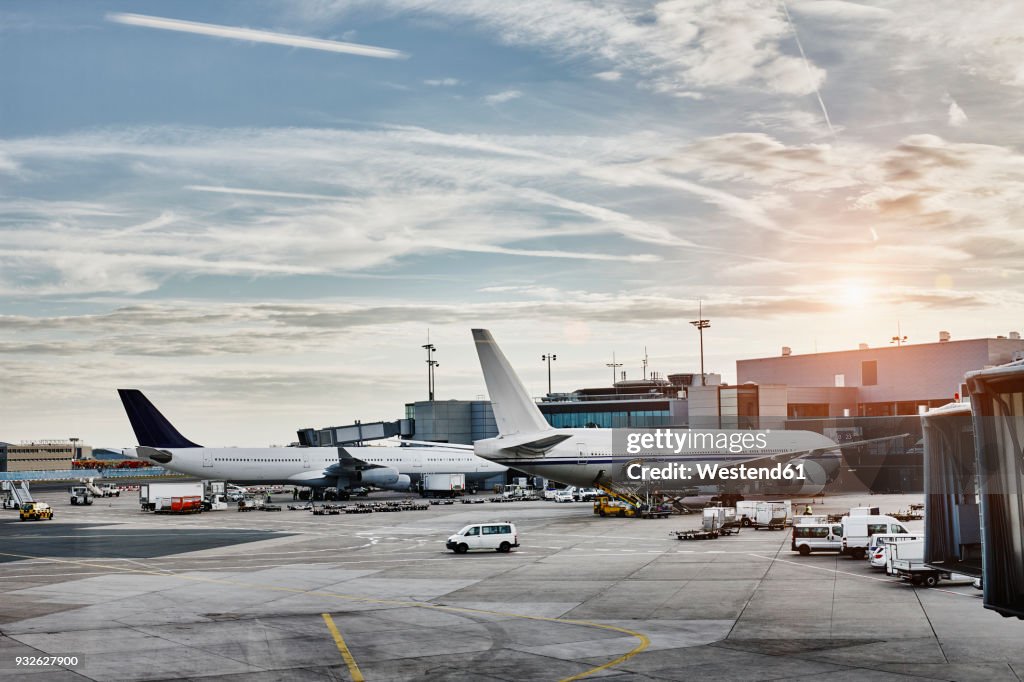 Airplanes and vehicles on the apron at sunset