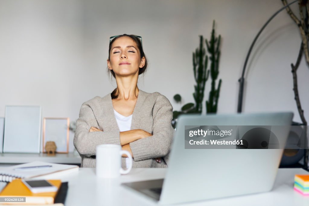 Young woman at home with laptop on desk having a break