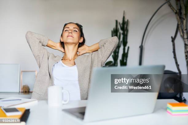 young woman at home with laptop on desk leaning back - connected mindfulness work stock pictures, royalty-free photos & images