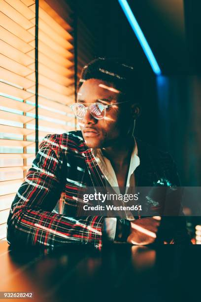 portrait of fashionable young man wearing checkered suit coat looking out of window - minder verzadiging stockfoto's en -beelden