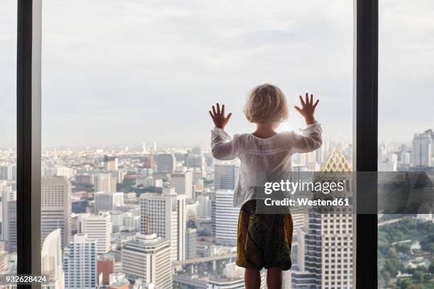 thailand, bangkok, little girl looking through window at cityscape - girl standing stock pictures, royalty-free photos & images