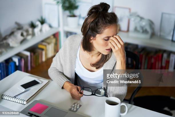 young woman at home at desk suffering headache - hoofdpijn vrouw stockfoto's en -beelden