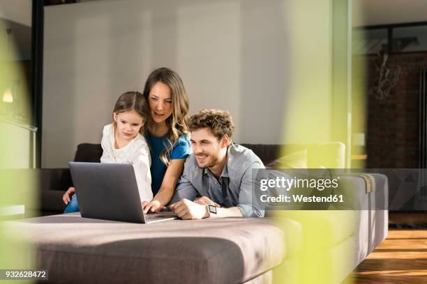 family using laptop on sofa at home - family laptop stock pictures, royalty-free photos & images