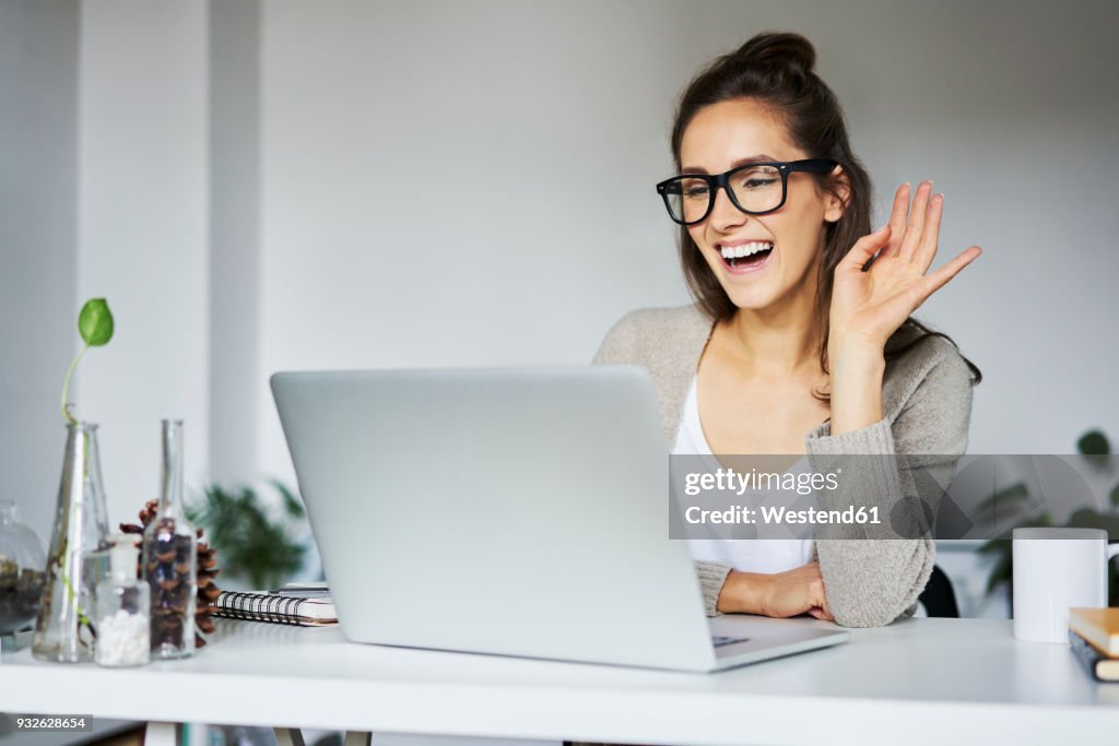 Young woman laughing during video chat at desk