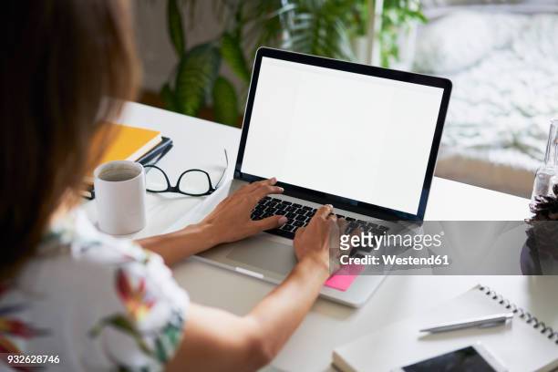 young woman working at desk with laptop - monitor foto e immagini stock