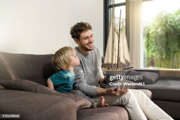 father and son with toy model ship on couch at home - air child play stock-fotos und bilder