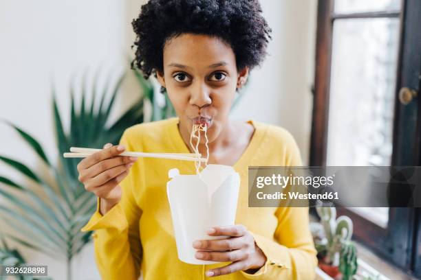young woman eating asian noodles for lunch with chopsticks - aziatische-noedels stockfoto's en -beelden