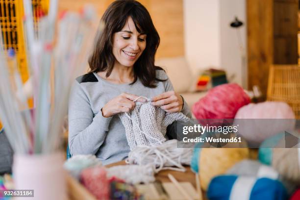 smiling woman at table knitting - puntos fotografías e imágenes de stock