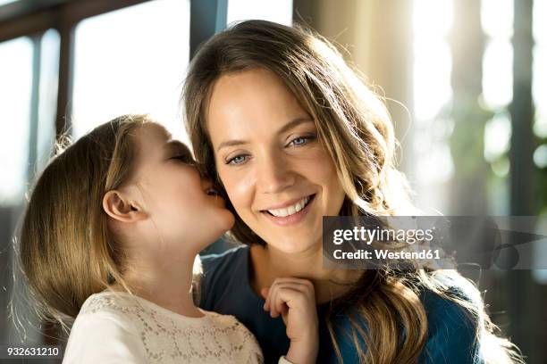 smiling girl whispering into her mother's ear - child whispering stock-fotos und bilder