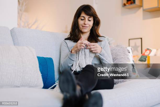 woman sitting on couch knitting - knitting stock pictures, royalty-free photos & images