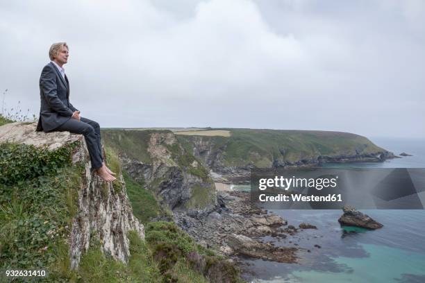 uk, cornwall, gwithian, businessman sitting at the coast looking at view - gwithian ストックフォトと画像