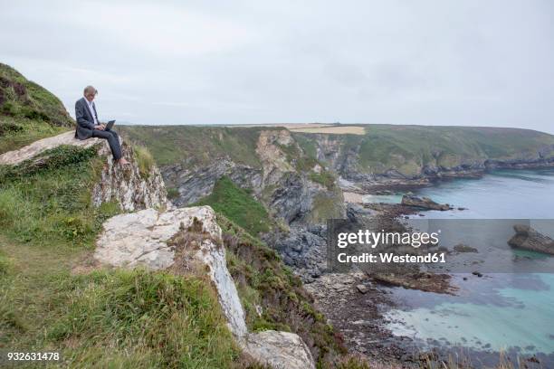 uk, cornwall, gwithian, businessman sitting at the coast using laptop - gwithian ストックフォトと画像