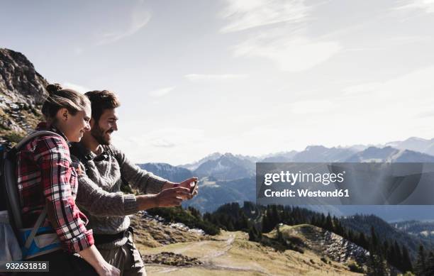 austria, tyrol, smiling young couple taking a selfie in mountainscape - tirol deelstaat stockfoto's en -beelden